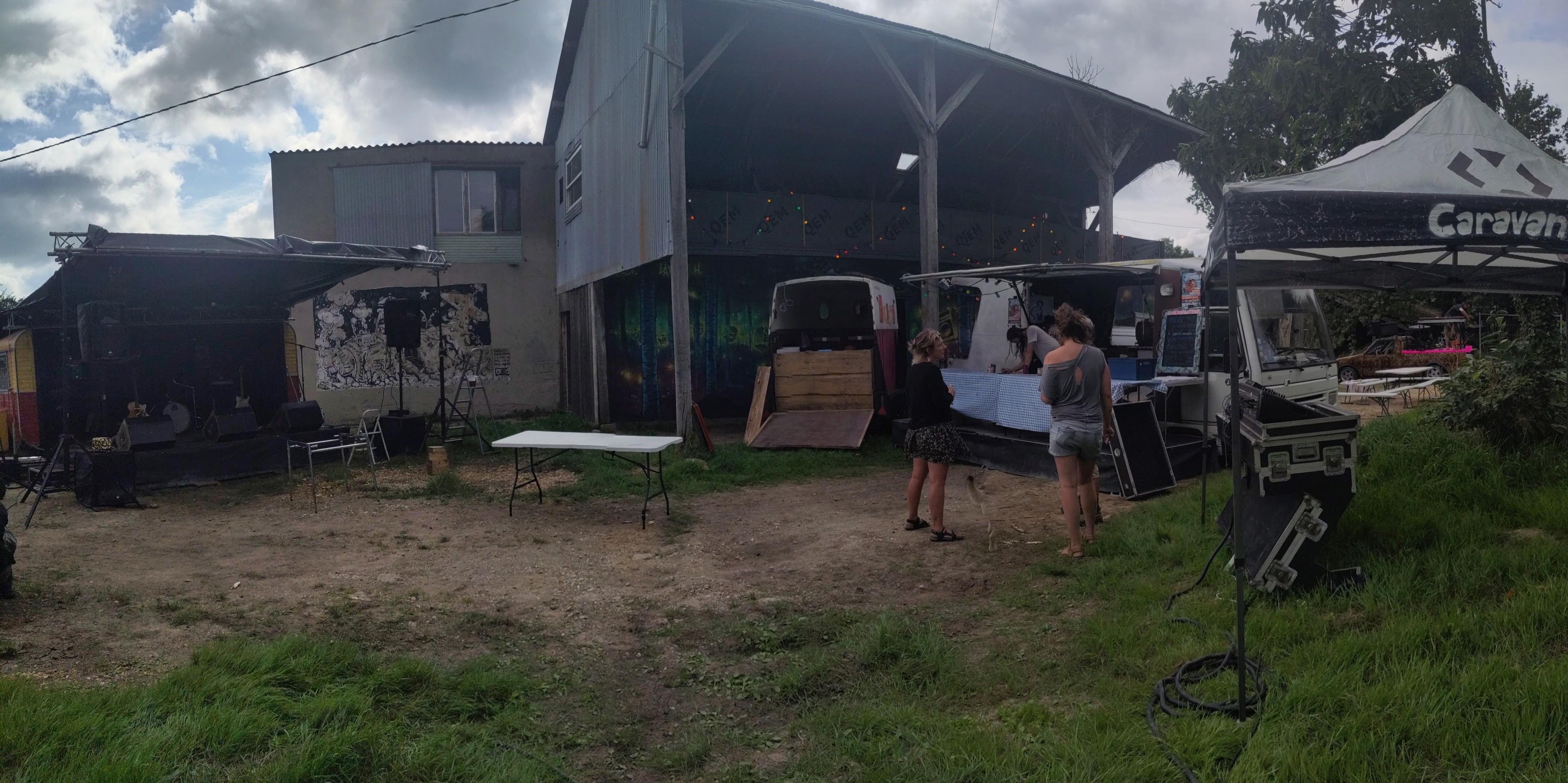 Photo d'ensemble de la scène caravane, du camion-bar et de la régie du Caravan Tour avec des fresques sur les bâtiments dans le fond